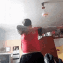 a man in a red shirt is standing in a room .
