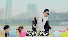 a man in a suit and tie is dancing on a beach and the words dat ass are on the screen .
