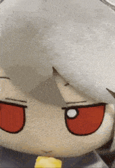 a close up of a stuffed animal with red eyes and a yellow object in its mouth