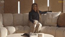 a woman sits on a couch in front of a wall that says harlem