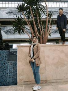 a man and a woman standing next to each other in front of a tree