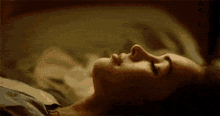 a woman is sleeping in a bed with her eyes closed .