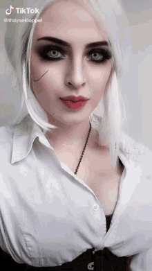 a woman with white hair is wearing a white shirt and a black corset ..