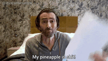 a man sitting on a bed with the words my pineapple is shit