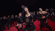 a group of women are dancing on a red carpet in front of photographers