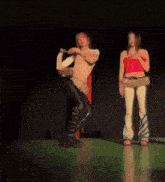 a woman in a red top is standing next to a man dancing on a stage