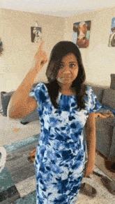 a woman in a blue floral dress is pointing upwards