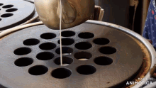a pot of liquid is being poured into holes on a stove with the words made in animatica below it