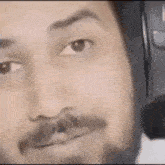 a close up of a man with a beard wearing headphones .