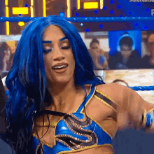 a female wrestler with blue hair is standing in a wrestling ring .