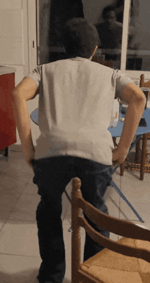 a man in a grey shirt is standing in front of a table and chairs