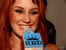 a woman holding a microphone that says rbd