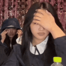 a girl covering her face with her hand while another girl looks on