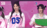 a girl in a pink jersey with the number 05 on it is standing next to another girl .