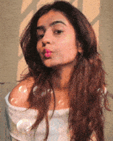 a woman wearing a white off the shoulder top is blowing bubbles