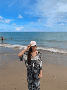 a woman wearing a pink hat stands on a sandy beach