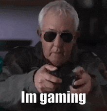 an elderly man wearing sunglasses is playing a video game while holding a controller .