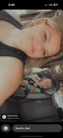 a woman is taking a selfie with a child in a car seat and the time is 2:35