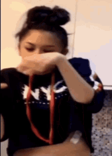a woman wearing a nyc shirt covering her face with her hand