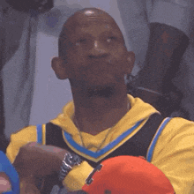 a man wearing a yellow nike jersey is sitting in a stadium with his eyes closed