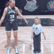 a woman wearing a phantom 20 jersey stands next to a little girl