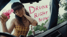 a woman holds a heart in front of a sign that says drunk right now on the windshield