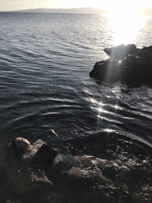 a person is laying in the water with the sun shining through the water
