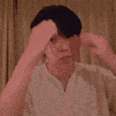 a man with his eyes closed is touching his head with his hands .