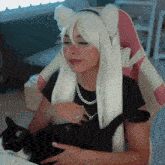 a woman in a white wig holds a black and white cat