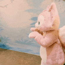 a stuffed animal in a pink squirrel costume is standing in front of a wall .