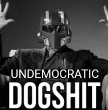 a black and white photo of a man wearing a helmet that says " undemocratic dogshit " on it