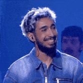 a man with silver hair and a beard is smiling and wearing earbuds