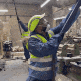 a man wearing a mask and safety vest is working in a workshop