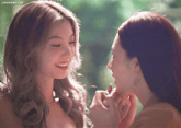 two women are touching each other 's faces and the words lingormgifs are on the bottom right