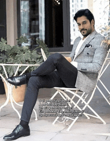 a man in a suit sits on a chair with his legs crossed in front of a table