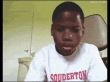 a young boy wearing a souderton t-shirt looks at the camera
