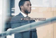 a man in a suit and tie is standing next to a railing and talking .