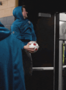 a person in a blue hoodie holds a soccer ball
