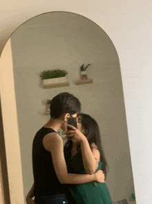 a man and a woman kissing in front of a mirror with the word love on the wall