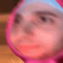 a blurry picture of a person 's face with a pink hood
