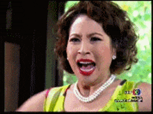 a woman wearing a pearl necklace and earrings is making a funny face with her mouth open .