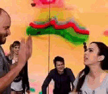 a man and woman are giving each other a high five in front of a painting .