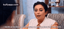 a woman is sitting in a chair and talking to another woman while talking about her pronouns .
