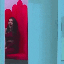 a woman in a red dress is sitting in a red chair