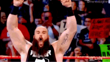 a wrestler with his arms in the air in front of a crowd