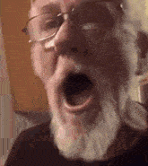 an older man with a beard and glasses is yawning .
