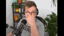 a man wearing glasses and a vans shirt covering his nose
