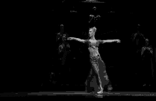 a woman is dancing in a black and white photo on a stage .