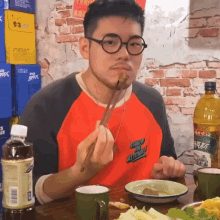a man wearing glasses and a shirt that says stand up for altitude is eating food