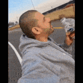 a man in a grey hoodie drinks from a bottle that says coca cola on it